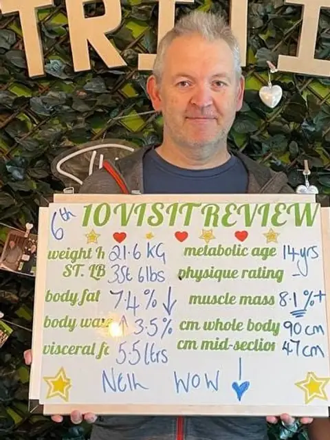 A man holds up his whiteboard results in the club room
